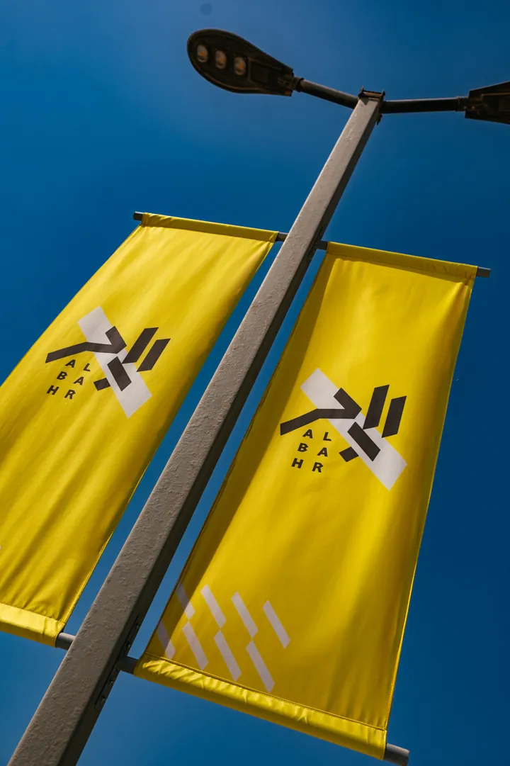 View photo: yellow Al Bahr flags against the sky.