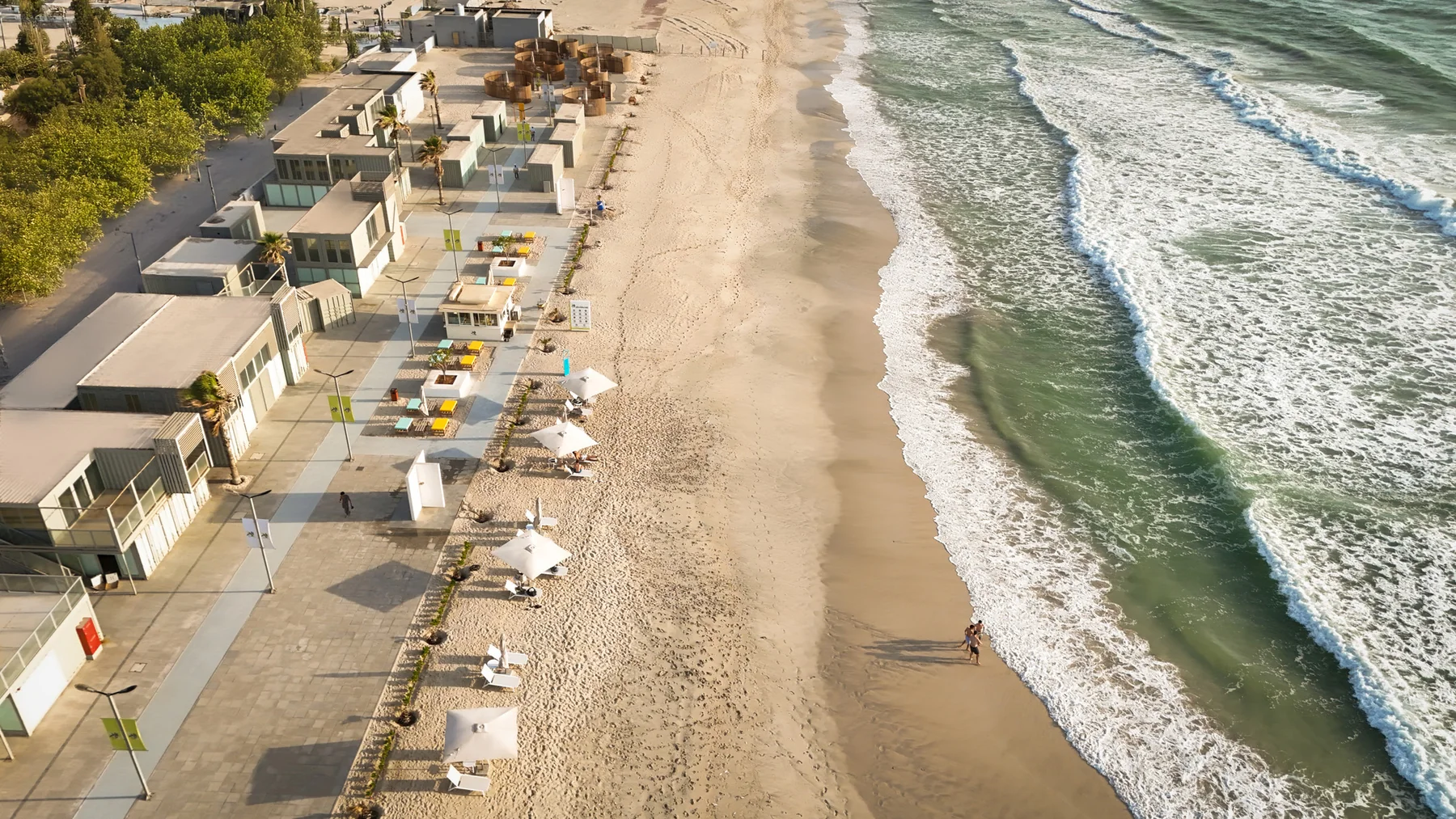 An aerial view of Al Bahr’s beachfront buildings, promenade and shore.